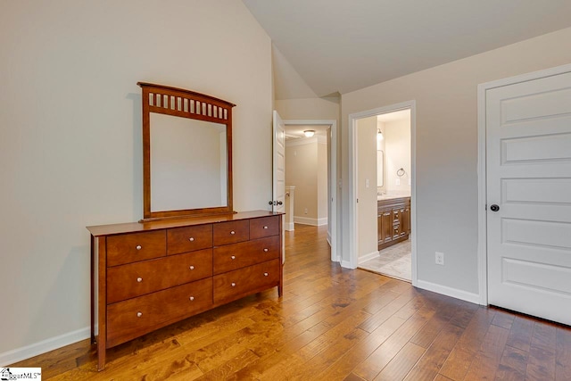 bedroom with ensuite bathroom and light wood-type flooring