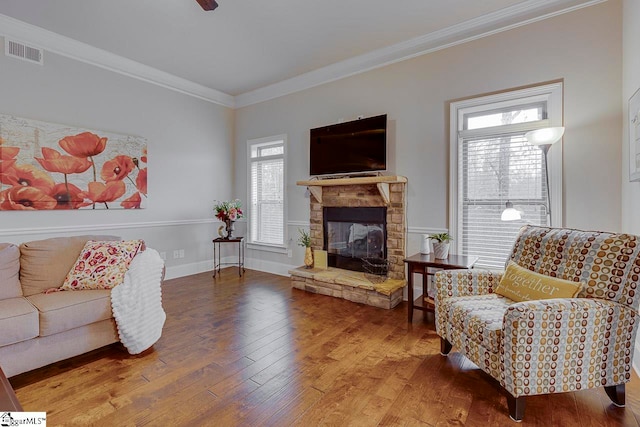 living room featuring a stone fireplace, wood-type flooring, and ornamental molding