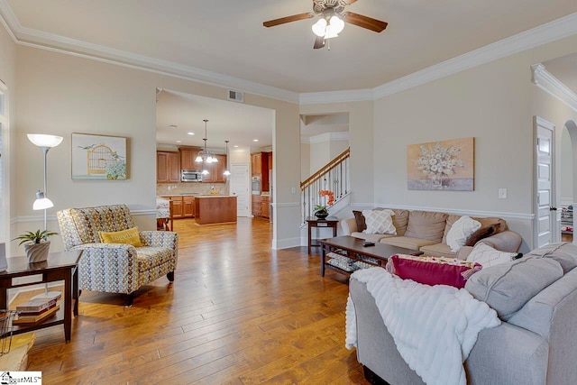 living room featuring hardwood / wood-style floors, ceiling fan, and crown molding