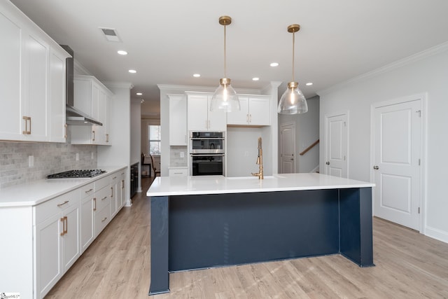 kitchen with white cabinetry, wall chimney exhaust hood, light hardwood / wood-style flooring, pendant lighting, and appliances with stainless steel finishes