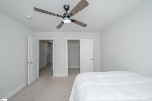 carpeted bedroom with a walk in closet, a closet, and ceiling fan