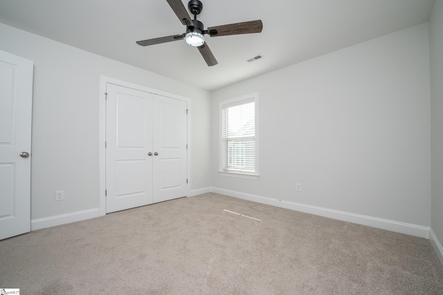 unfurnished bedroom featuring ceiling fan, a closet, and light carpet