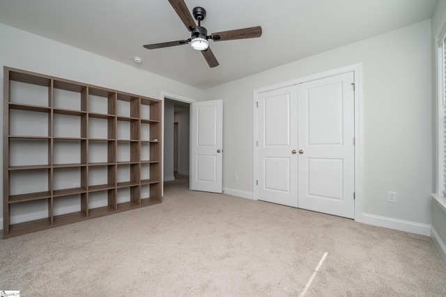 unfurnished bedroom featuring a closet, light colored carpet, and ceiling fan