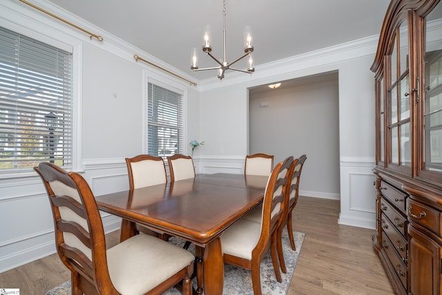 dining area with an inviting chandelier, light wood-type flooring, and ornamental molding