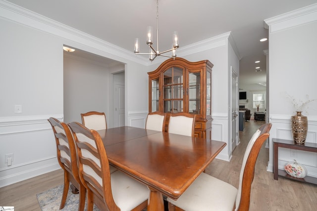 dining area featuring crown molding, light hardwood / wood-style flooring, and an inviting chandelier