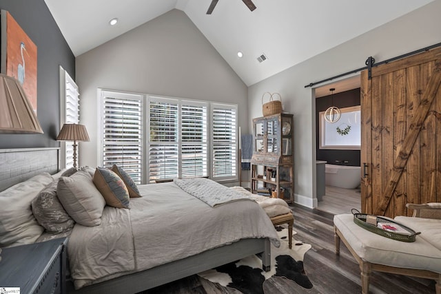 bedroom with high vaulted ceiling, ensuite bathroom, ceiling fan, a barn door, and dark hardwood / wood-style flooring