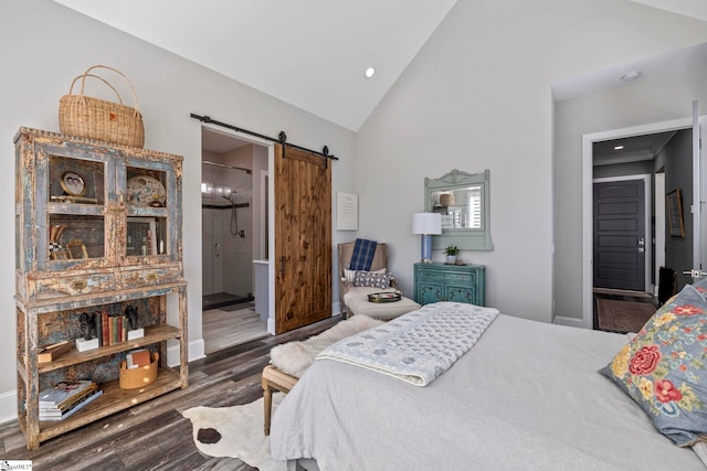 bedroom with dark hardwood / wood-style floors, a barn door, connected bathroom, and vaulted ceiling