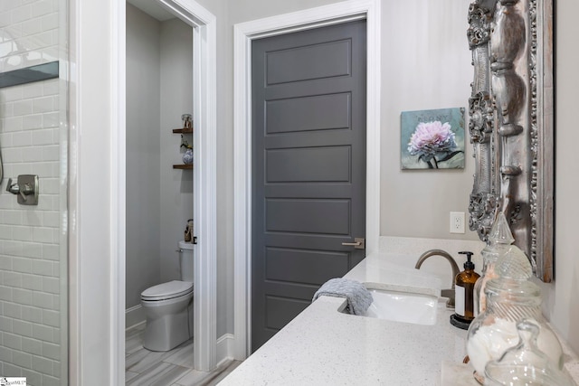 bathroom featuring vanity, toilet, and a tile shower