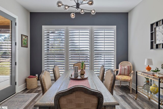 dining area with hardwood / wood-style floors, plenty of natural light, and a notable chandelier