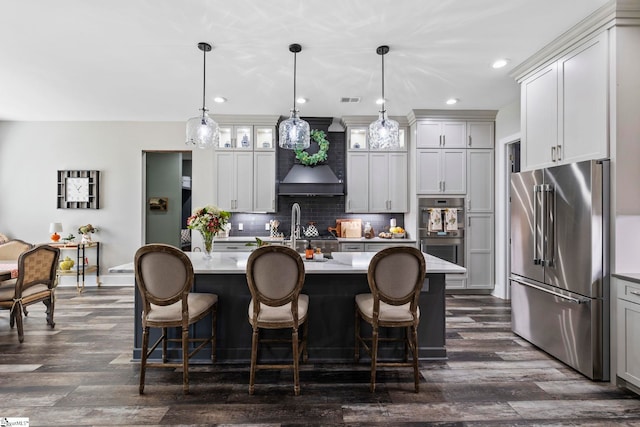 kitchen featuring decorative light fixtures, an island with sink, and appliances with stainless steel finishes