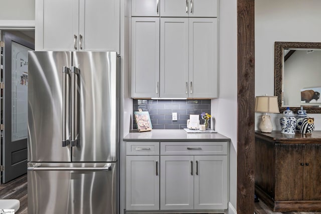 kitchen featuring backsplash, white cabinetry, dark wood-type flooring, and stainless steel refrigerator