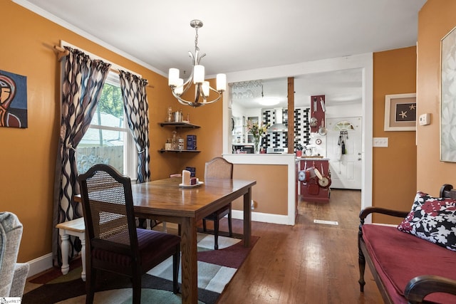 dining space featuring dark hardwood / wood-style floors, crown molding, and an inviting chandelier