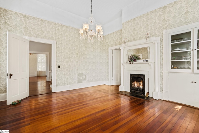 unfurnished living room featuring a notable chandelier and dark hardwood / wood-style floors