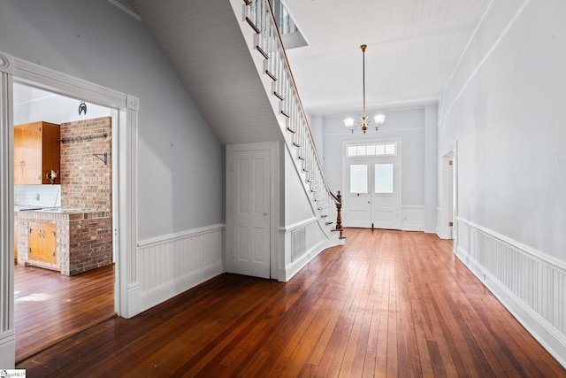 entrance foyer with vaulted ceiling, dark hardwood / wood-style flooring, and a chandelier