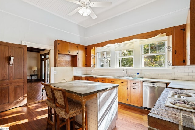 kitchen with dishwasher, decorative backsplash, sink, and light hardwood / wood-style flooring