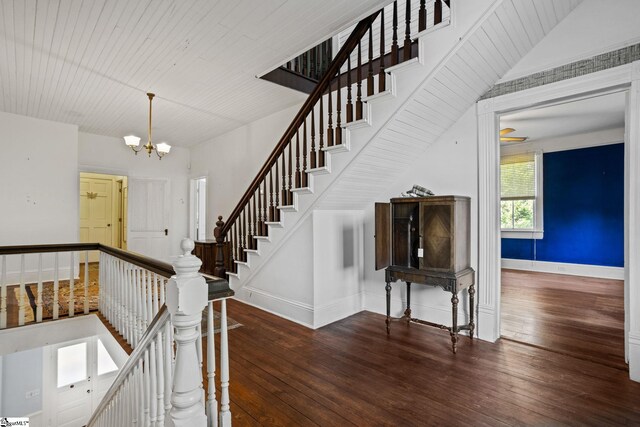 stairs featuring hardwood / wood-style floors and an inviting chandelier