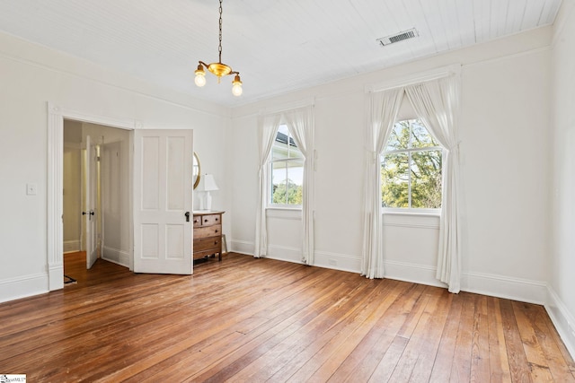 unfurnished bedroom featuring hardwood / wood-style floors and a notable chandelier