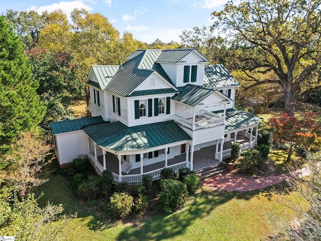 exterior space featuring a balcony, a porch, and a front yard