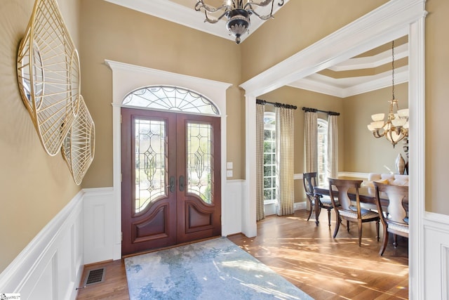 entrance foyer featuring a notable chandelier, a healthy amount of sunlight, wood-type flooring, and french doors