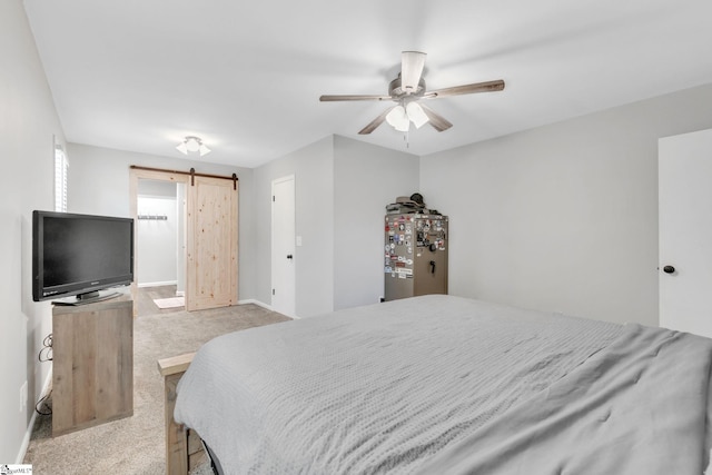 bedroom with a barn door, stainless steel fridge, ceiling fan, and light carpet