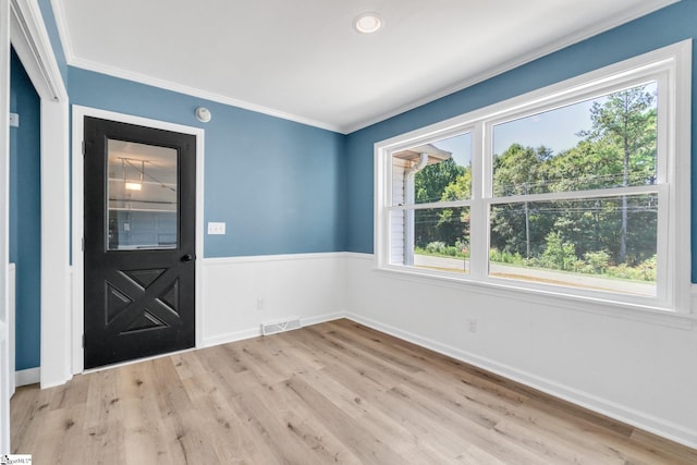 foyer featuring a wealth of natural light, crown molding, and light hardwood / wood-style floors