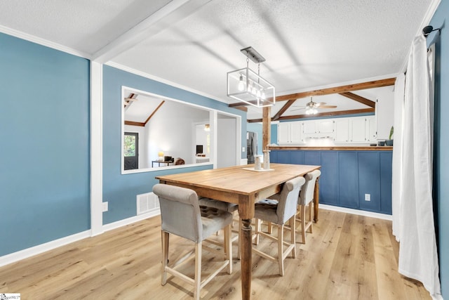 dining room featuring ceiling fan, vaulted ceiling with beams, light hardwood / wood-style floors, a textured ceiling, and ornamental molding