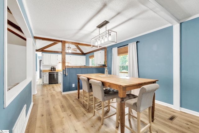 dining room with ceiling fan, vaulted ceiling with beams, light wood-type flooring, a textured ceiling, and ornamental molding