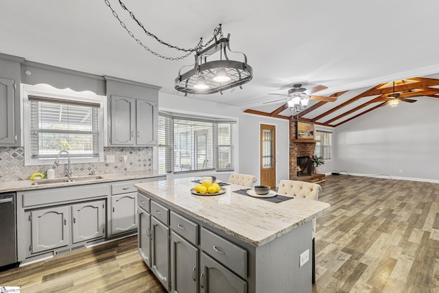 kitchen featuring a fireplace, lofted ceiling with beams, a kitchen island, and a healthy amount of sunlight