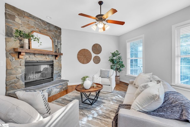 living room with a fireplace, wood-type flooring, a wealth of natural light, and ceiling fan