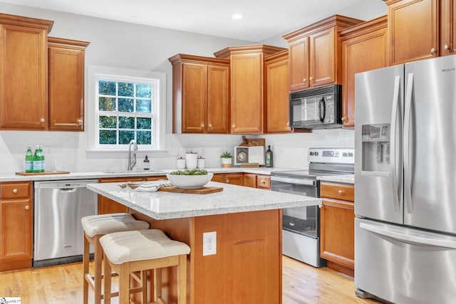 kitchen featuring a kitchen bar, stainless steel appliances, sink, light hardwood / wood-style flooring, and a kitchen island