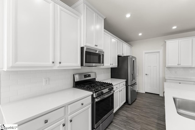 kitchen with sink, tasteful backsplash, dark hardwood / wood-style floors, white cabinets, and appliances with stainless steel finishes