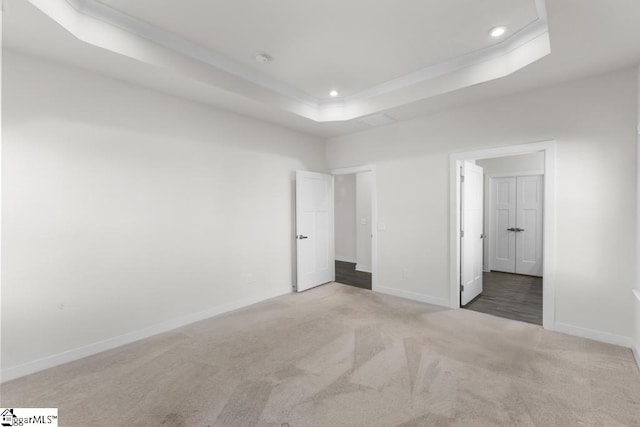 unfurnished bedroom featuring light carpet and a tray ceiling