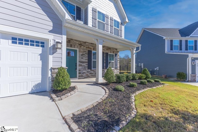 entrance to property with covered porch, a garage, and a lawn