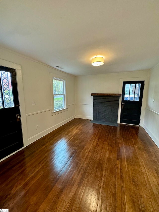 unfurnished living room featuring dark hardwood / wood-style flooring, a brick fireplace, and plenty of natural light