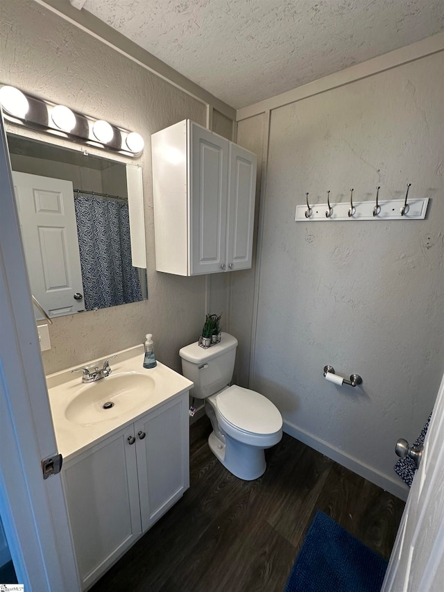 bathroom with a shower with shower curtain, a textured ceiling, vanity, hardwood / wood-style flooring, and toilet