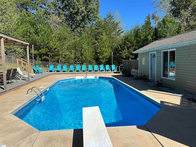 view of swimming pool with a patio and a diving board