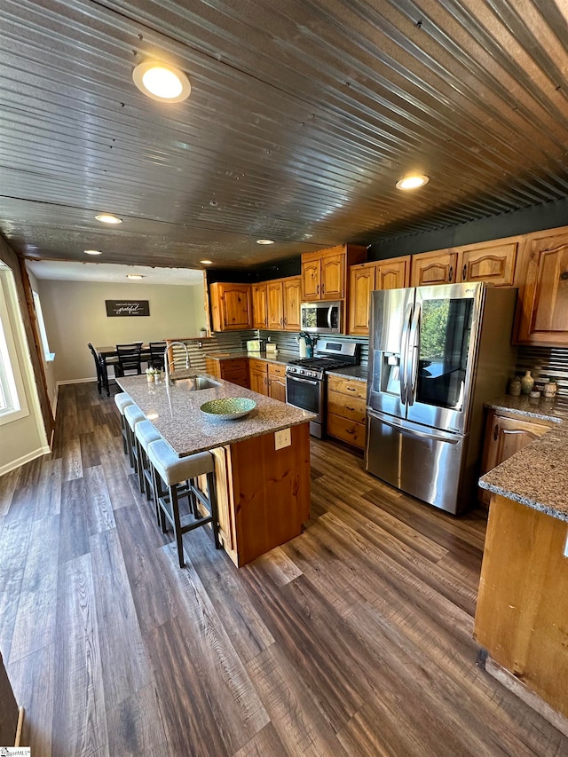 kitchen with a breakfast bar, dark wood-type flooring, sink, a kitchen island, and stainless steel appliances