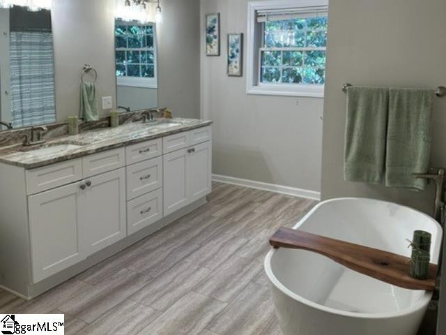 bathroom featuring a bath, vanity, and wood-type flooring