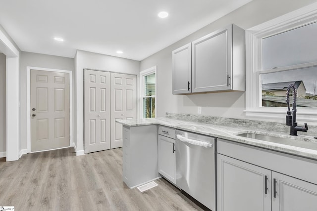 kitchen featuring dishwasher, sink, light stone countertops, light hardwood / wood-style floors, and kitchen peninsula