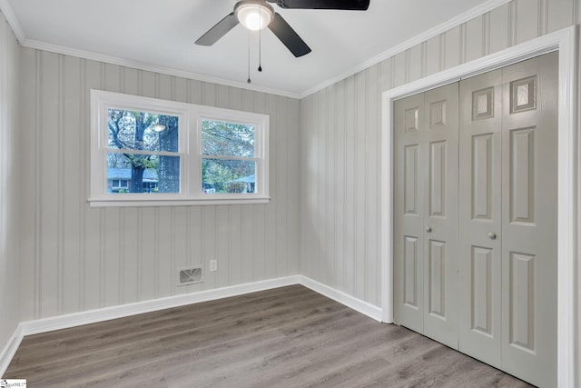 unfurnished bedroom featuring ceiling fan, ornamental molding, light hardwood / wood-style flooring, and a closet