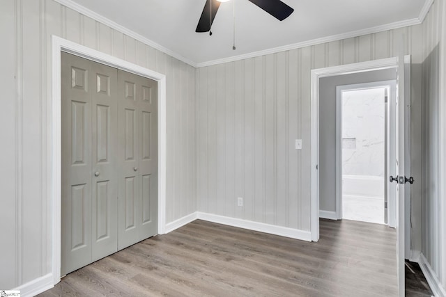 unfurnished bedroom with ceiling fan, a closet, crown molding, and light wood-type flooring