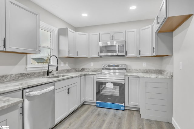 kitchen featuring light stone countertops, sink, light hardwood / wood-style flooring, white cabinets, and appliances with stainless steel finishes