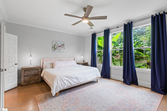 bedroom featuring ceiling fan, wood-type flooring, and ornamental molding