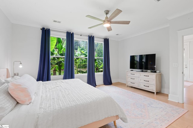 bedroom with light wood-type flooring, ceiling fan, and ornamental molding