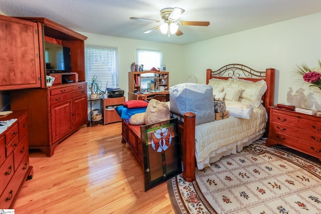 bedroom featuring ceiling fan, light wood-type flooring, and a textured ceiling