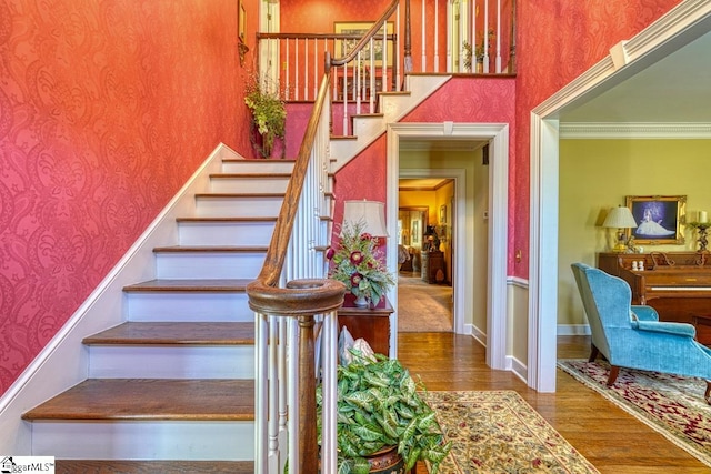 stairway with hardwood / wood-style flooring and crown molding