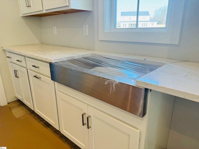 kitchen with white cabinetry and light stone counters