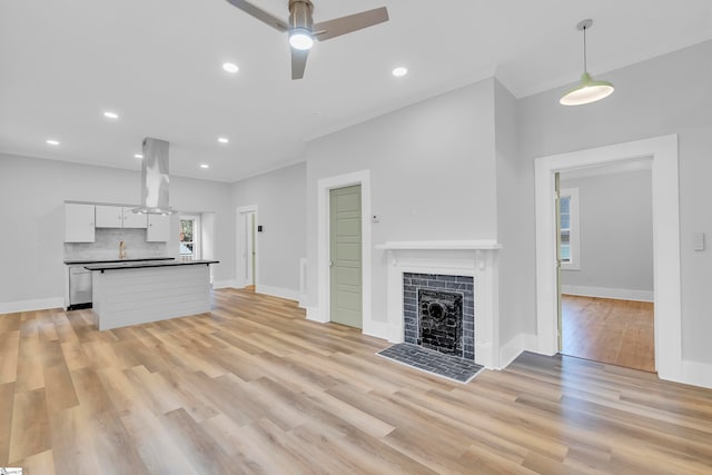 unfurnished living room with ceiling fan, light hardwood / wood-style floors, and a fireplace