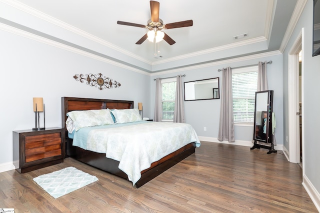 bedroom with wood-type flooring, a raised ceiling, ceiling fan, and crown molding