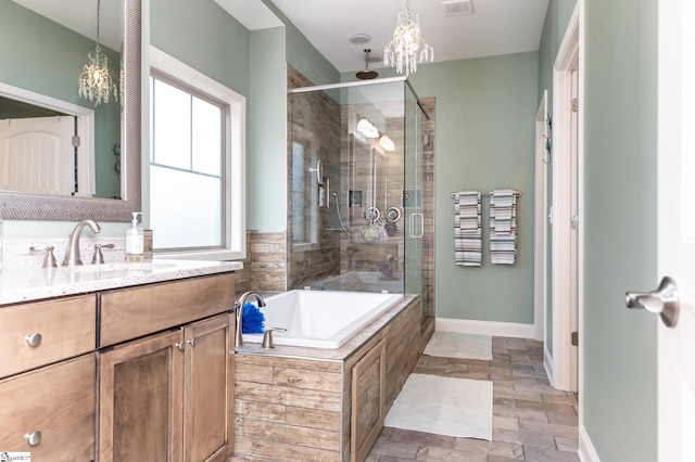 bathroom featuring vanity, independent shower and bath, and an inviting chandelier